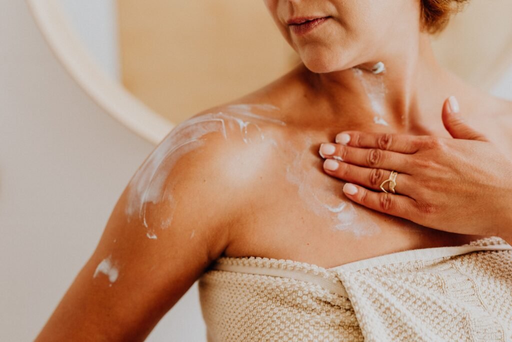 une femme qui s'applique une crème hydratante même sur son cou , ses bras et son décolleté